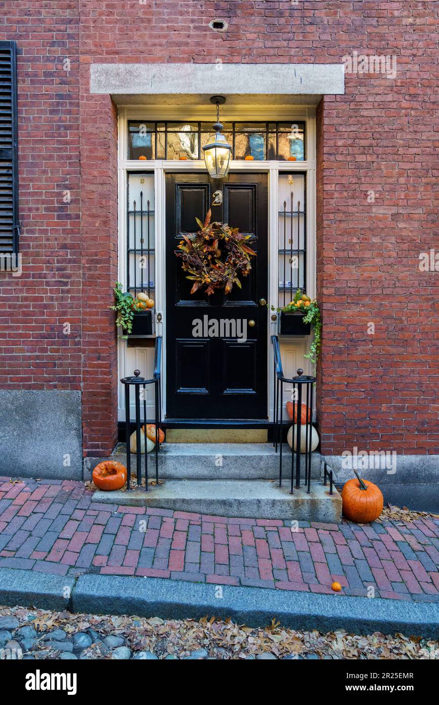 Boston, Massachusetts - November 29, 2018: Acorn Street Beacon Hill house during fall harvest with American Flag and cobblestone alley in Boston Stock Photo