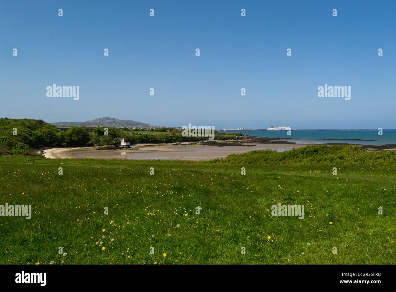View across sandy beach to Holyhead ferry Port from Penrhos Country