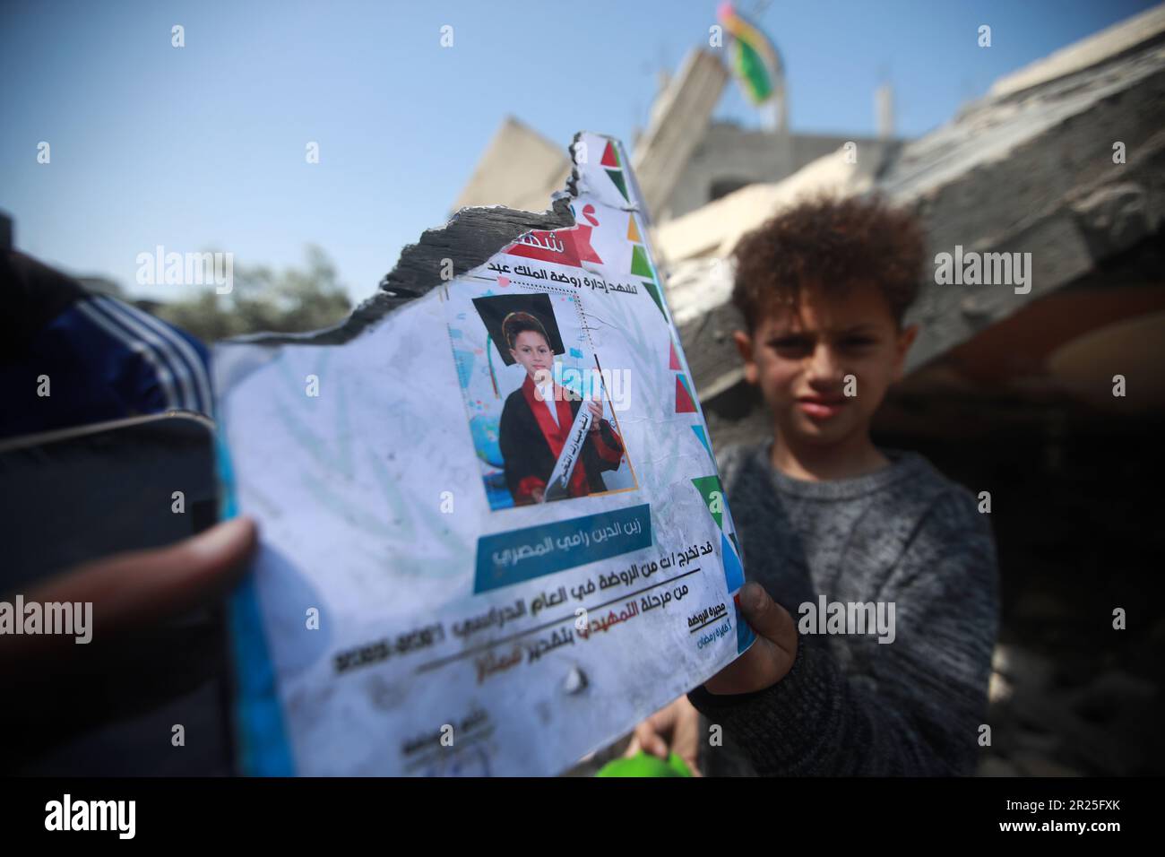 Portrait of a Palestinian boy holding a torn papaer cutting of his. His house was destroyed in the Israeli airstrike in Deir Al-Balah in central Gaza Strip. This is following the recent fighting between Islamic Jihad militant group and Israel in Gaza. Palestine. Stock Photo