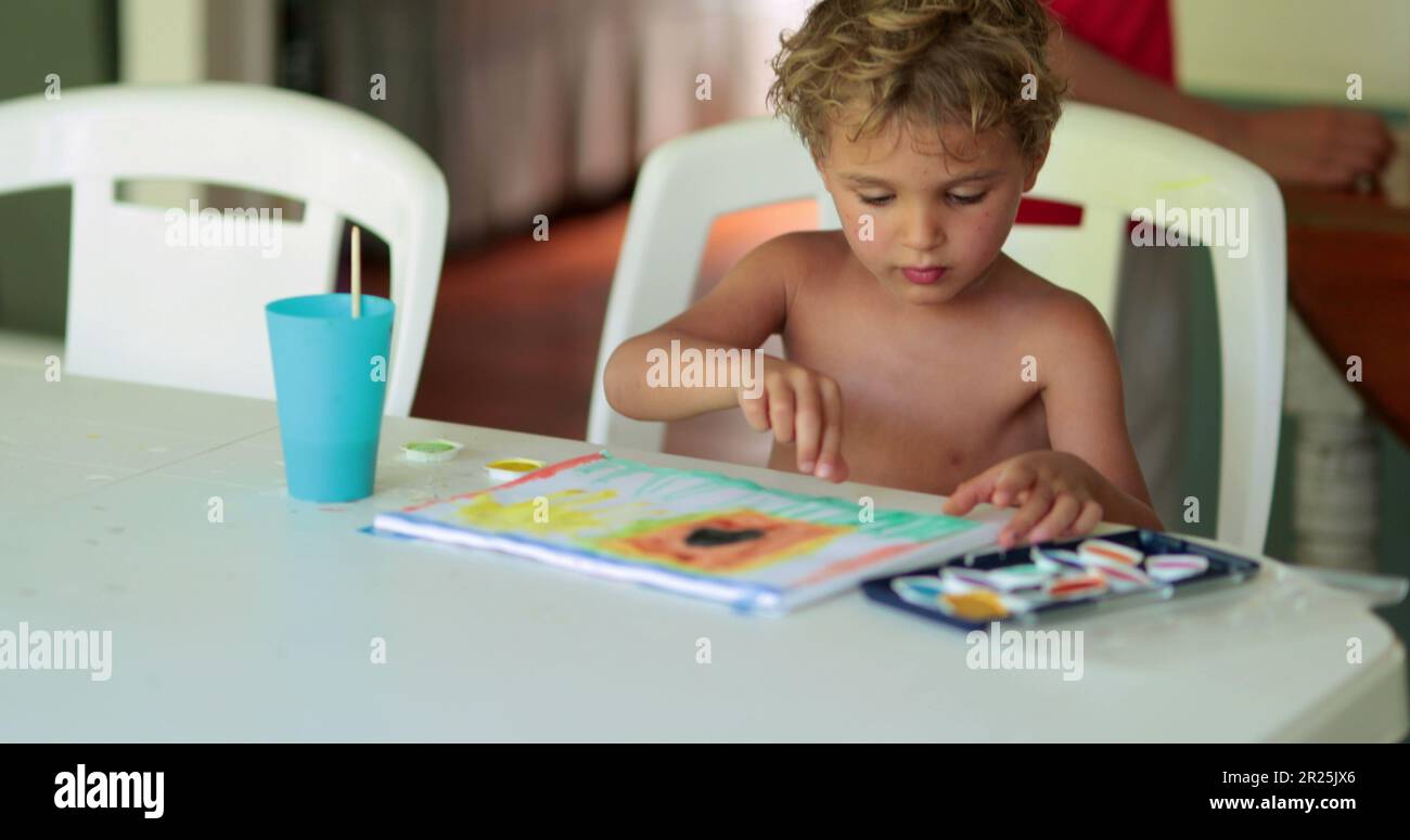 Toddler child boy creating and crafting aquarelle paint homework assignement Stock Photo