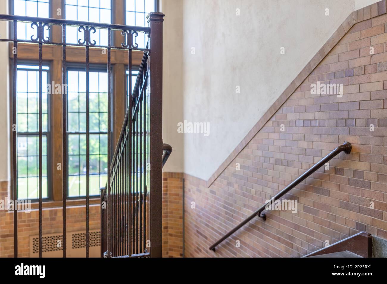 Nondescript stairway, hallway, with windows and brown railing, in a typical old US institutional building. Stock Photo