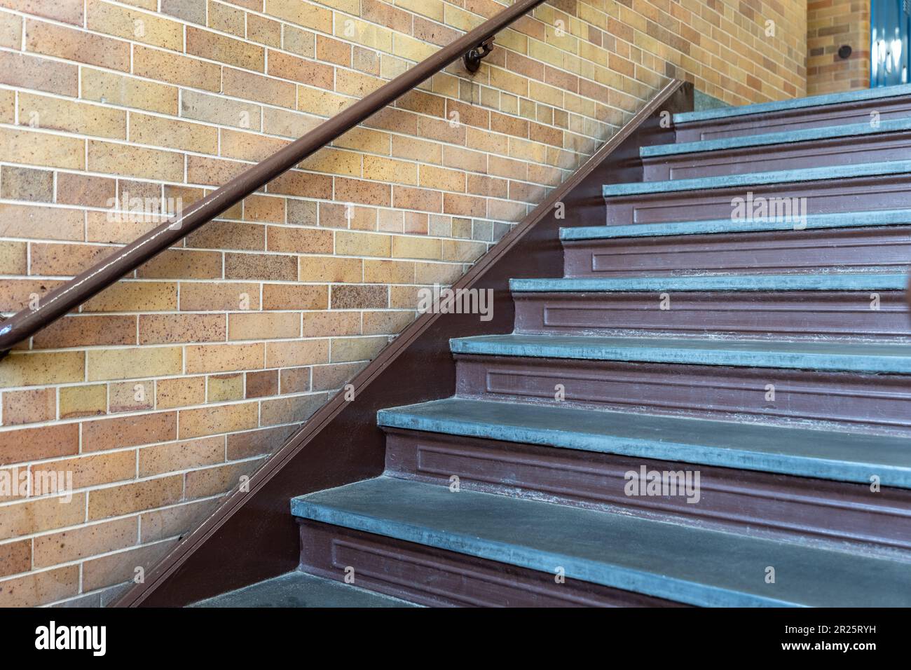 Nondescript interior stairway with a brown railing on a brick wall, in ...