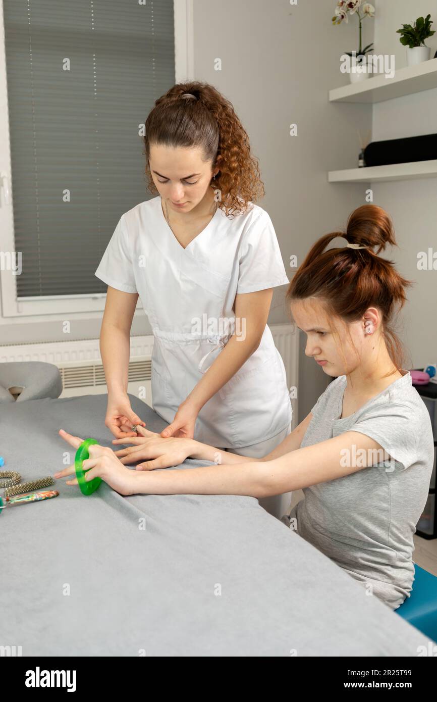 Doctor Neurologist Stretches Fingers Of Child with Disability. Physical