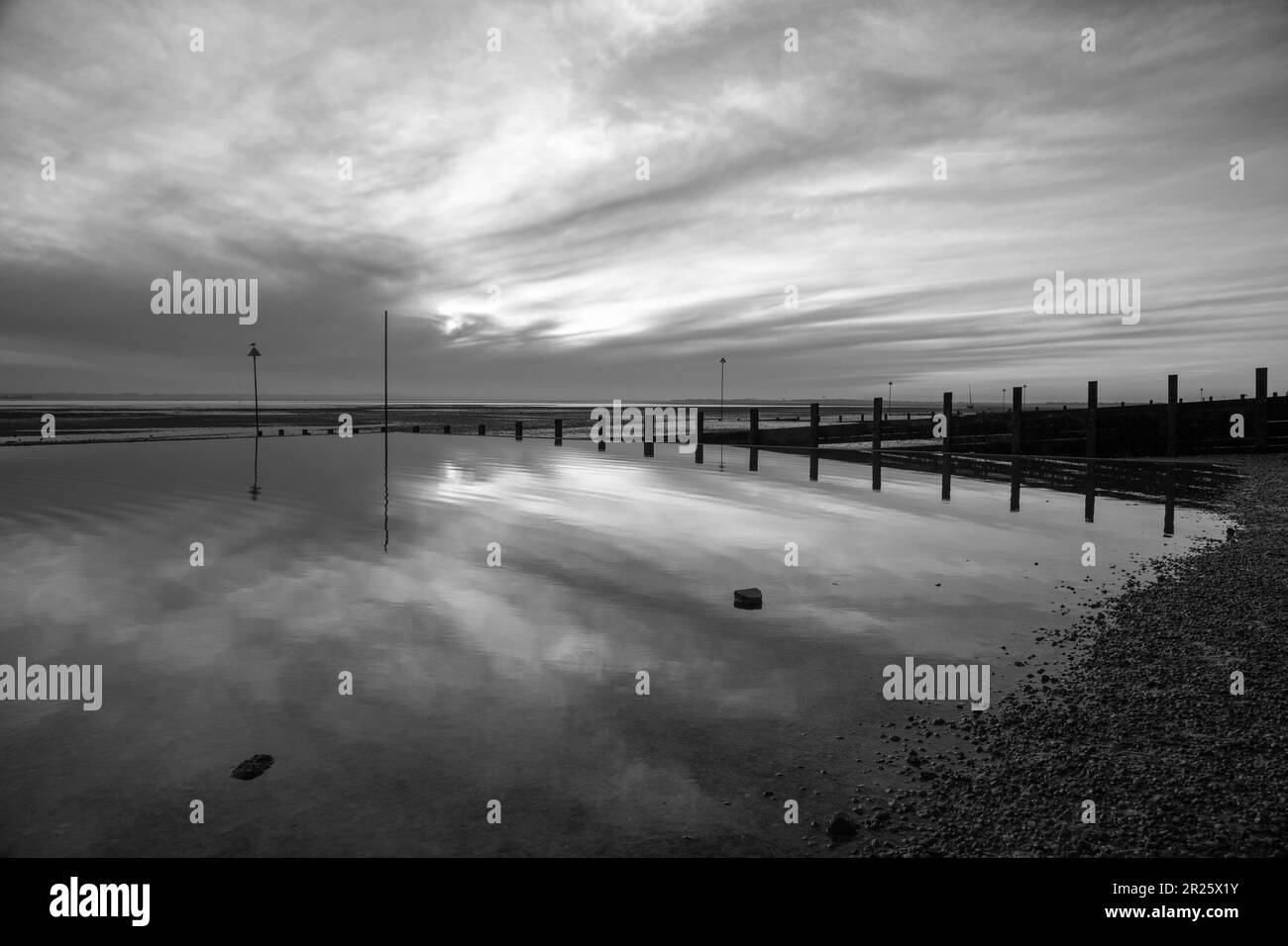 Black and white image of a winter sunset on Westcliff beach, near Southend-on-Sea, Essex, England, United Kingdom Stock Photo