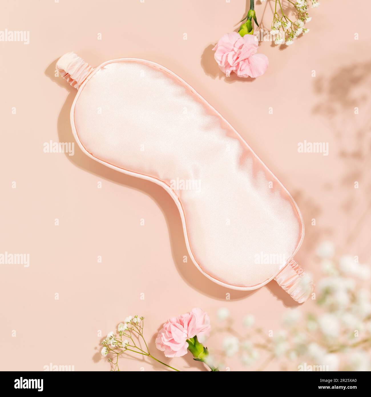 Pink mask for sleep and tender spring flowers on pink background Stock Photo