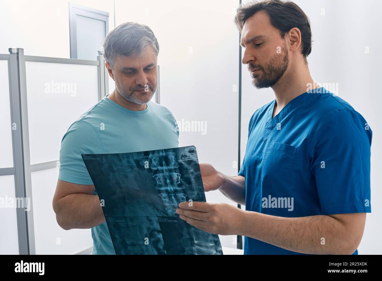 doctor showing MRI image of spine to patient during medical consultation for analysis and treatment of back disease. Examination and treatment of back Stock Photo