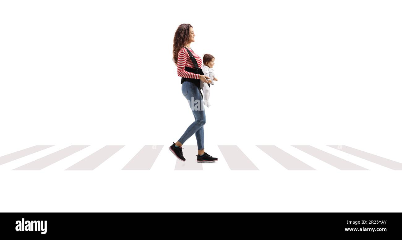 Full lenght shot of a young mother with a babay in a carrier walking at pedestrian crossing isolated on white background Stock Photo