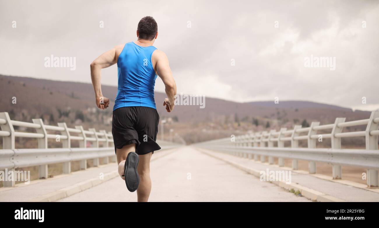 Rear shot of a man running over a bridge Stock Photo