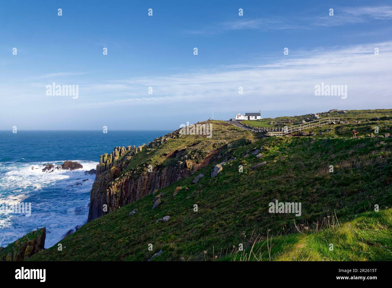 Waves breaking on The Peal, Dr Syntax's Head with First and Last House, Land's End, Cornwall, UK Stock Photo