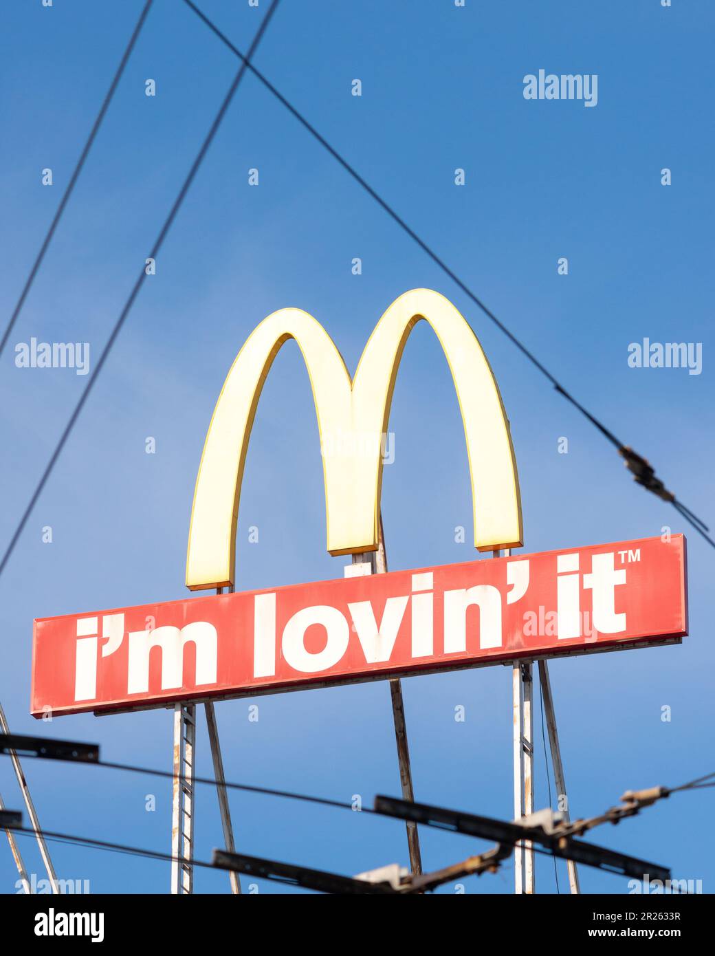 McDonald's logo and sign as seen through overhead lines or streetcar wires in urban environment Stock Photo