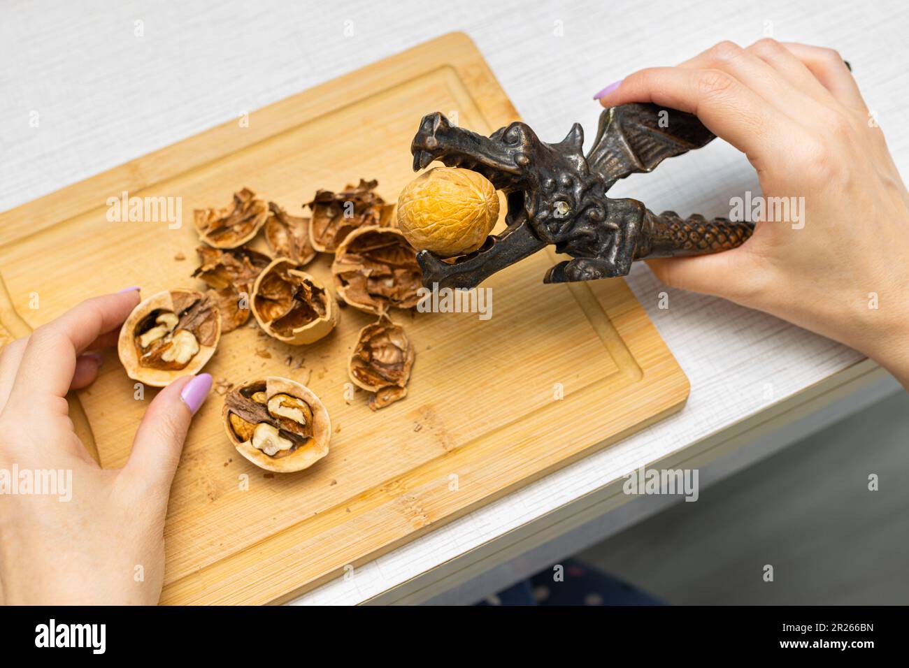 woman cracking walnuts with a handheld nutcracker. nut cracker for