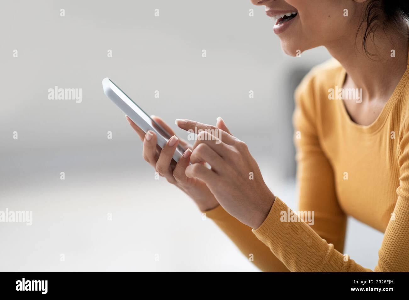 Smiling Young Woman Using Modern Smartphone At Home, Side View Stock Photo