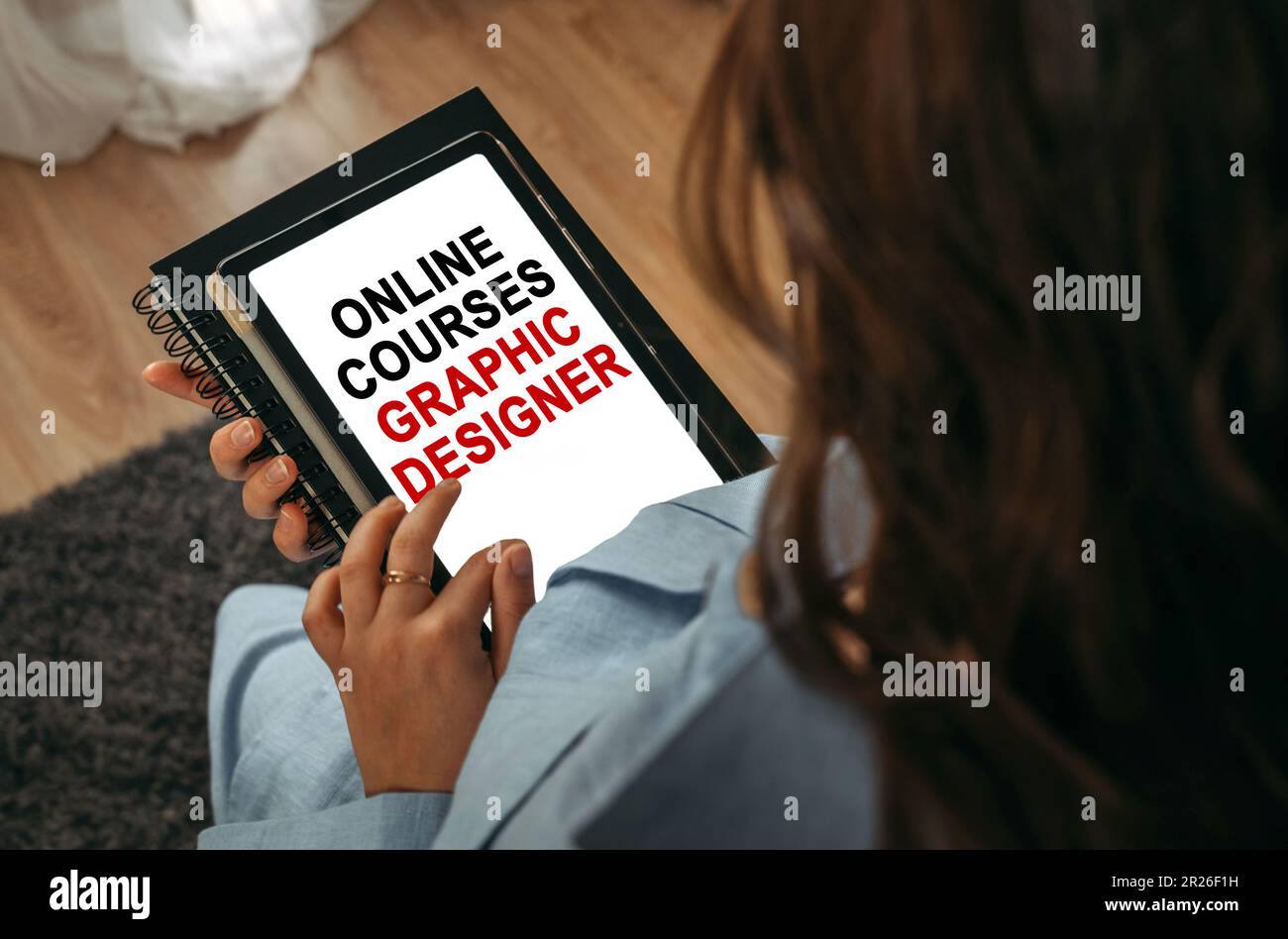 Online learning concept. A woman holds a tablet in her hands on the screen of which it is written - online courses Graphic designer Stock Photo