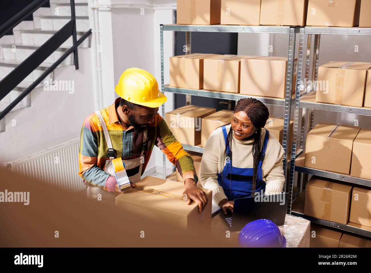 Distribution center workers checking merchandise inventory on laptop ...