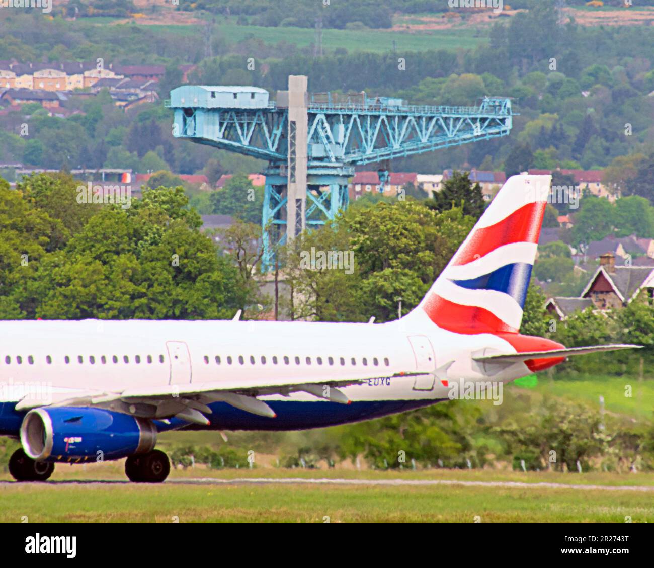 glasgow airport  british airways plane with clydebank shipbuilding crane Stock Photo
