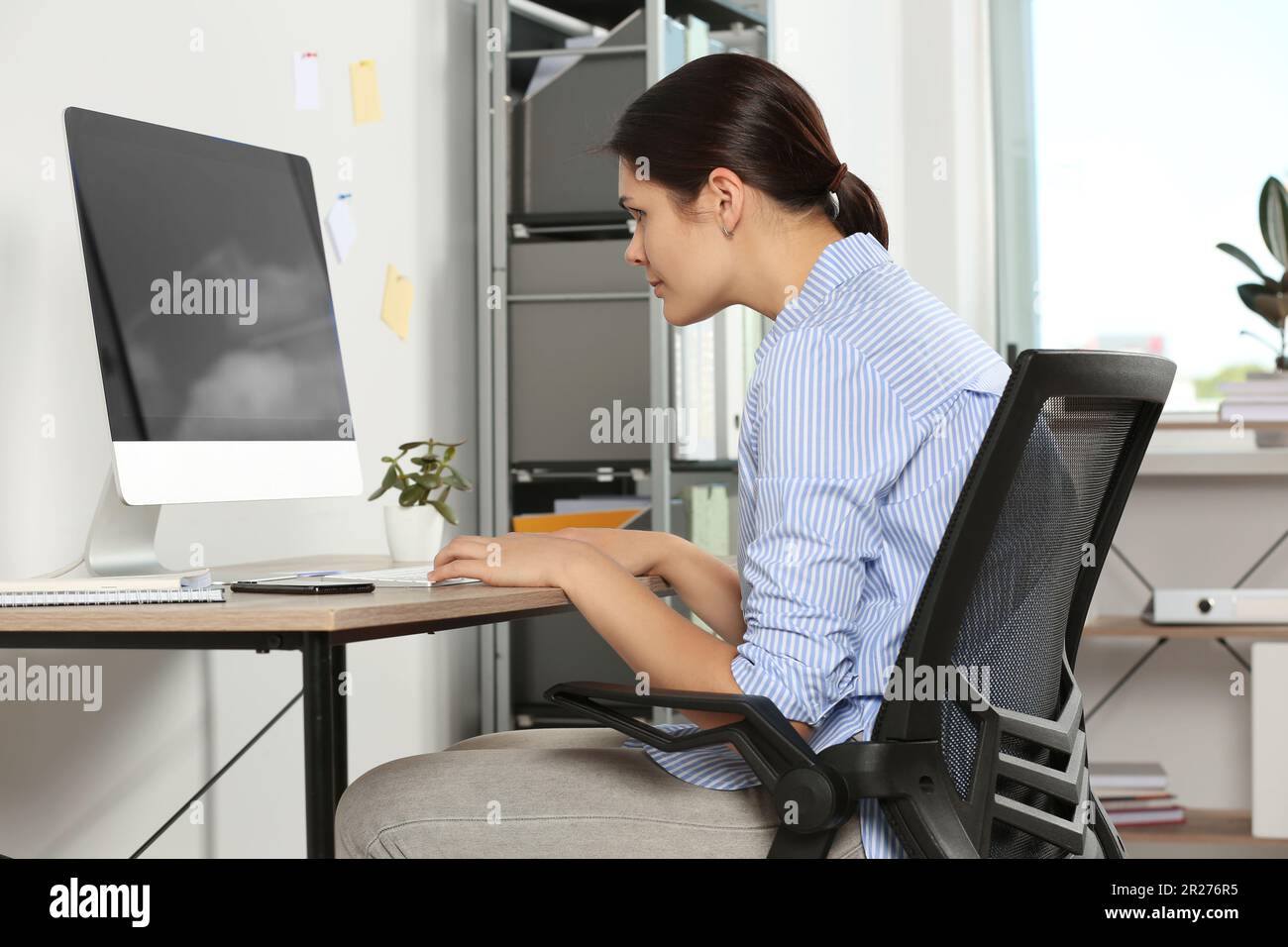 https://c8.alamy.com/comp/2R276R5/young-woman-with-bad-posture-sitting-at-workplace-in-office-symptom-of-scoliosis-2R276R5.jpg
