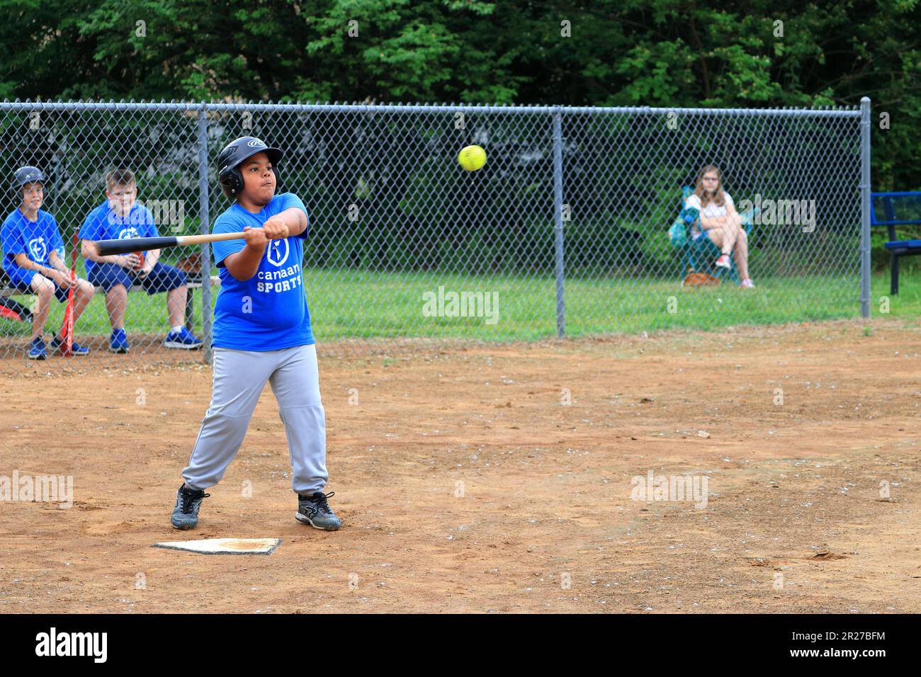 African American preteen boy batting during a softball game Stock