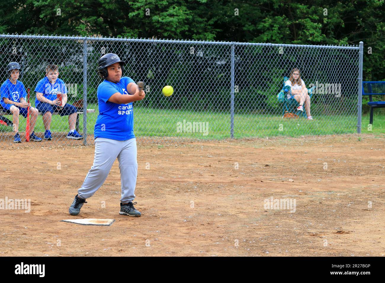 African American preteen boy batting during a softball game Stock