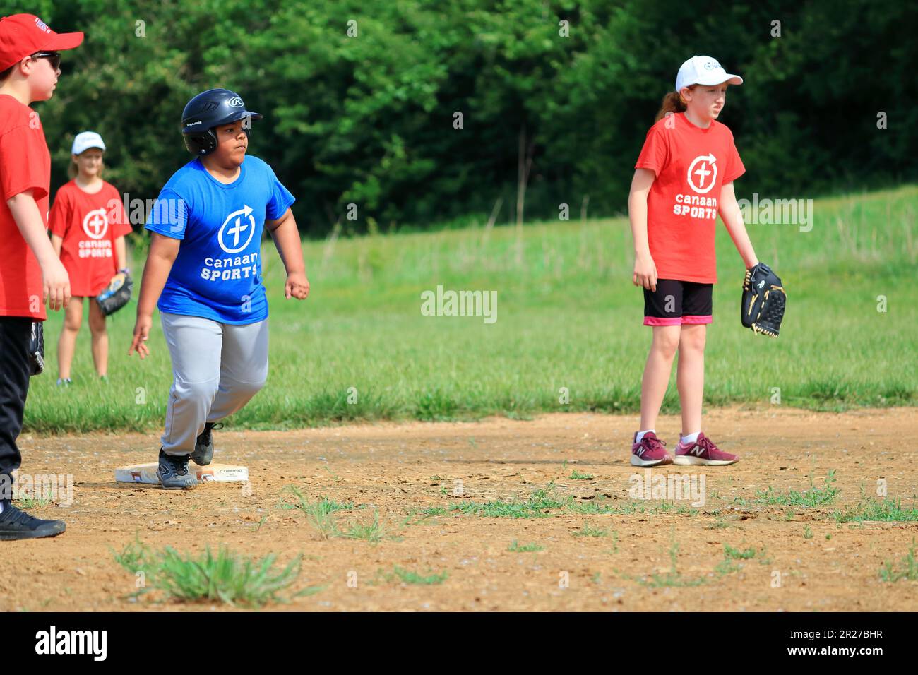 Preteen African American boy running bases during softball game Stock