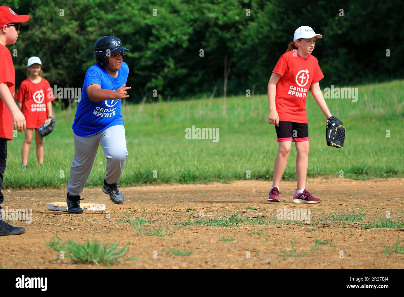 Preteen African American boy running bases during softball game Stock