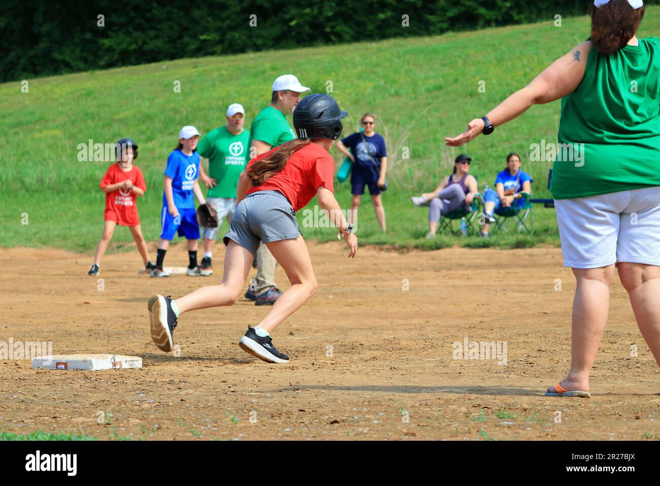Preteen girls running towards home plate during a softball game Stock Photo