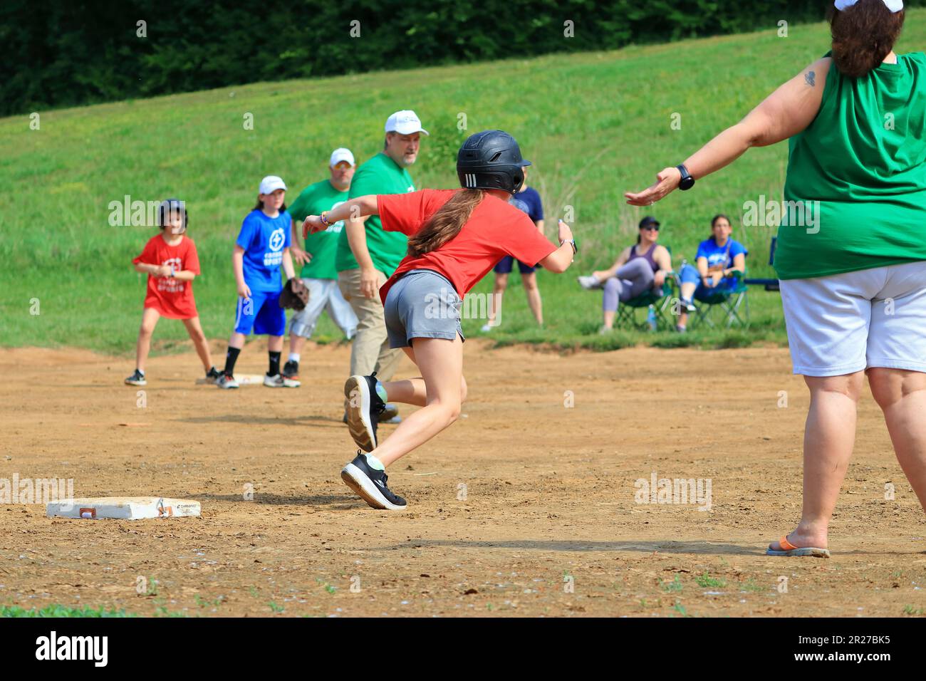 Preteen girls running towards home plate during a softball game Stock Photo