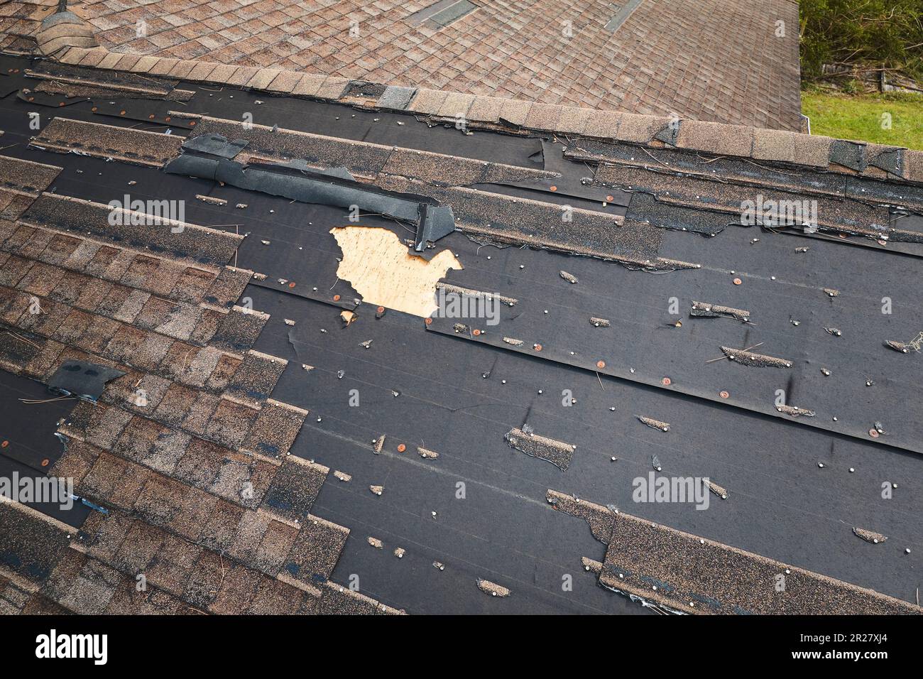 Damaged house roof with missing shingles after hurricane Ian in Florida