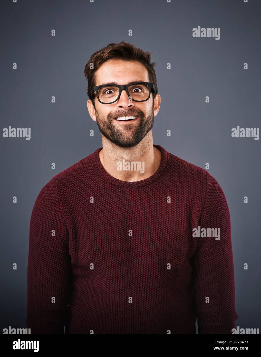 Making a face. Studio shot of a handsome young man pulling funny faces against a gray background. Stock Photo