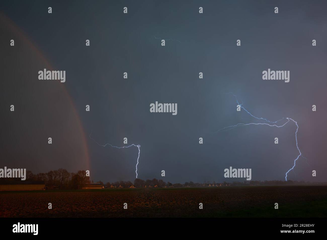 Dramatic view of a lightning storm with rainbow over the plains Stock Photo