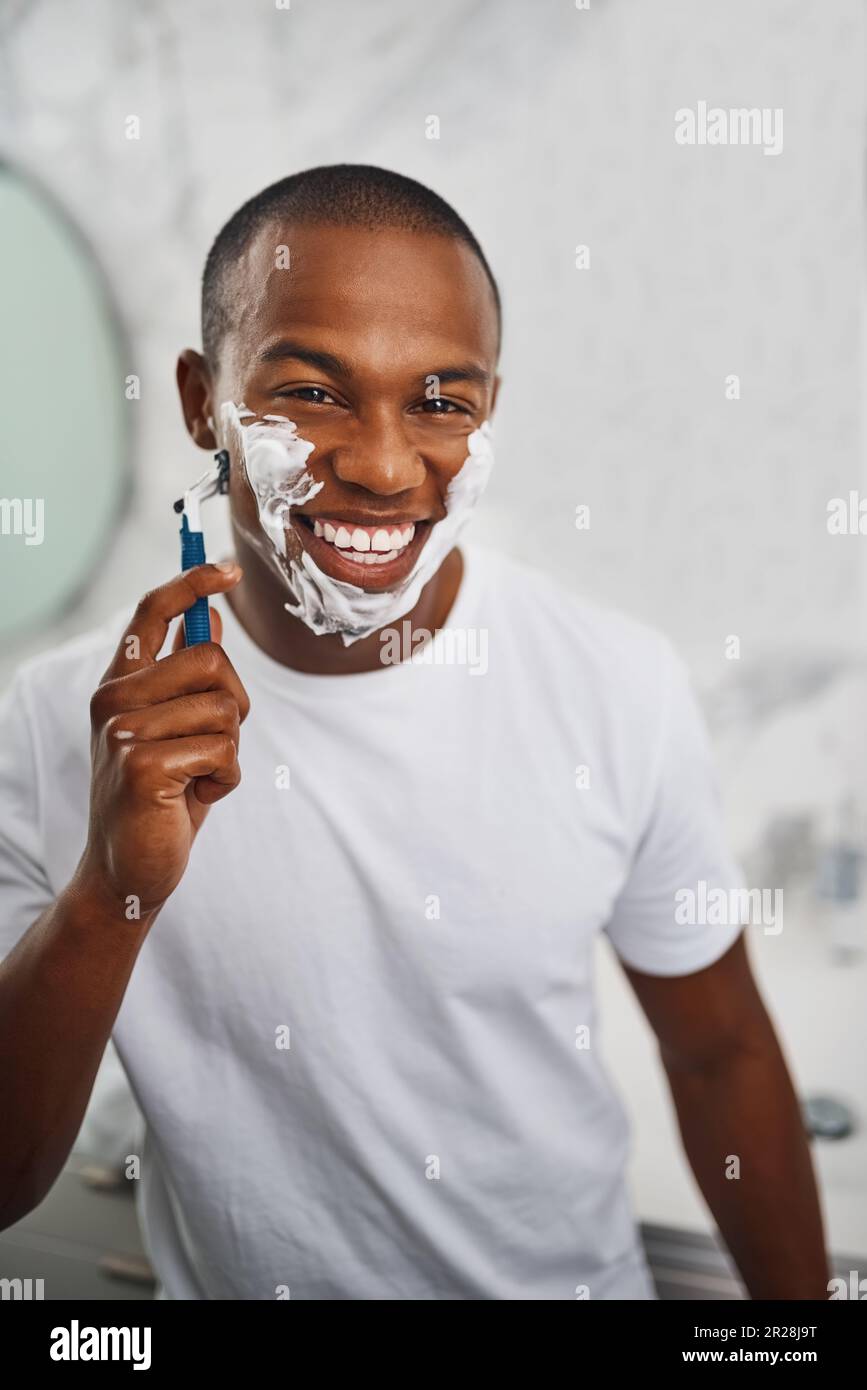Black man, smile and shaving with blade, soap or grooming in mirror for