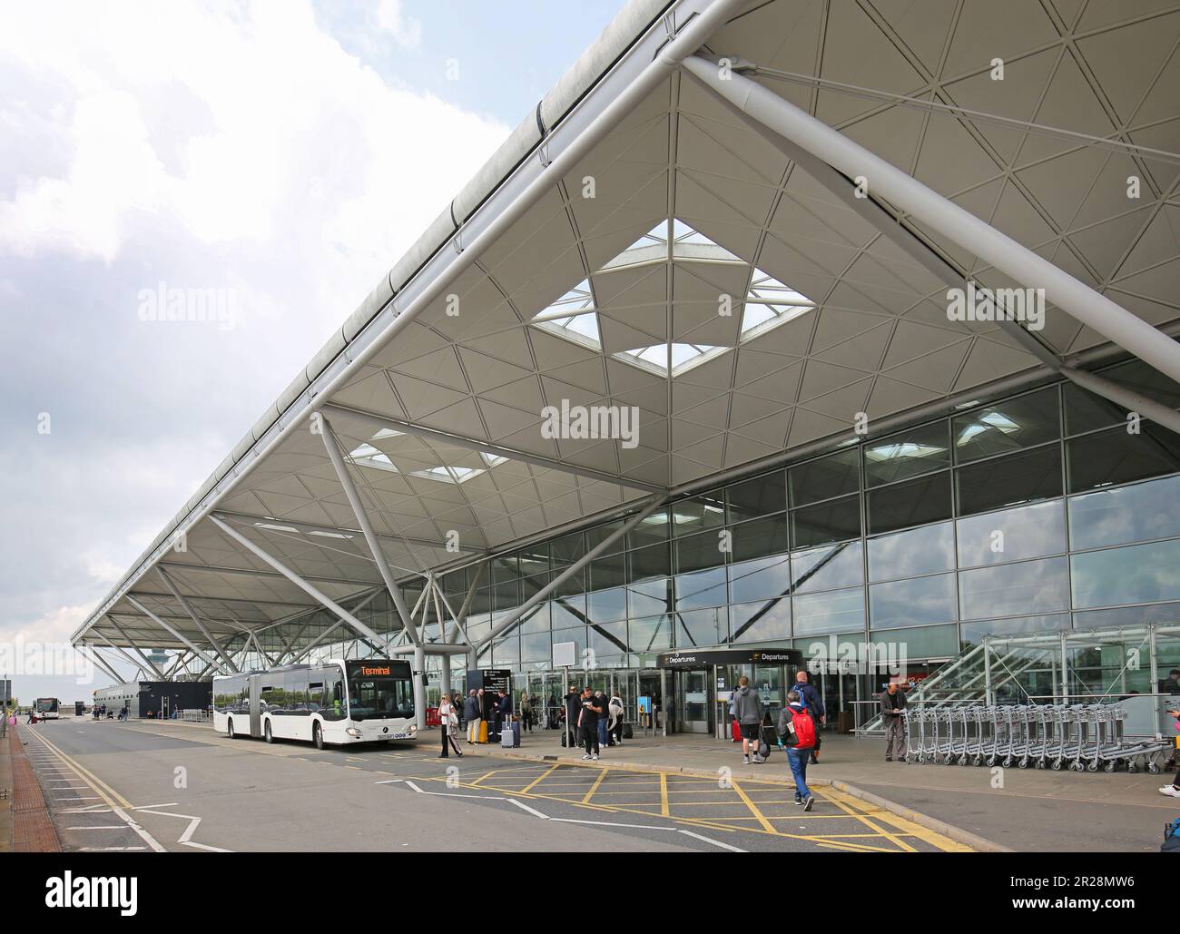 Stansted Airport, UK. A Car Park shuttle bus drops passengers in front of the main terminal building Stock Photo
