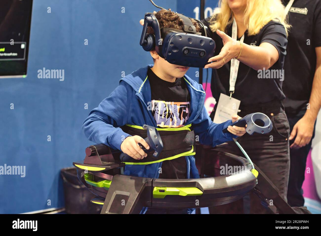 A young boy playing an immersive virtual reality treadmill machine with 360 degree headset and hand-controlled control pads Stock Photo