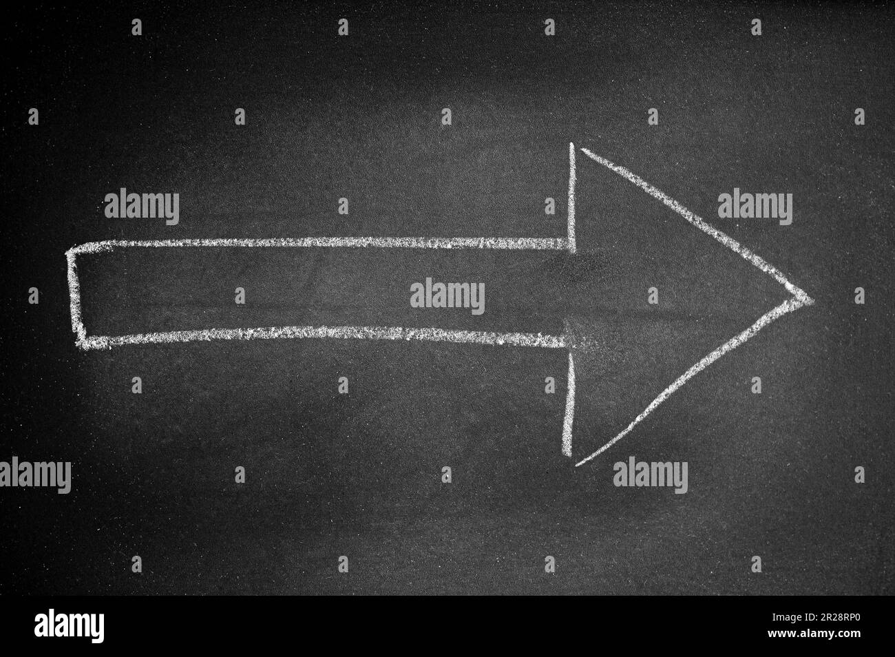 White arrow drawn on a black board with chalk indicating a direction Stock Photo