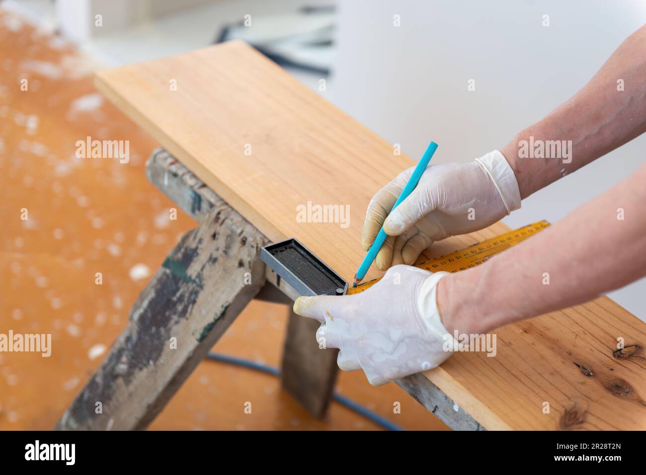 Hands of a builder marking the line on wood with pencil. Home refurbishment do it yourself project. Stock Photo