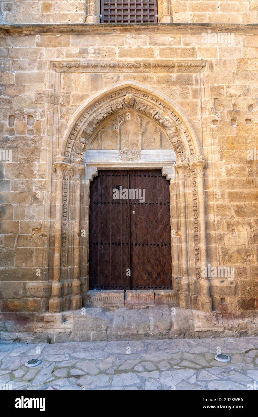 The old wooden door in the ornate stone wall of the church Stock Photo