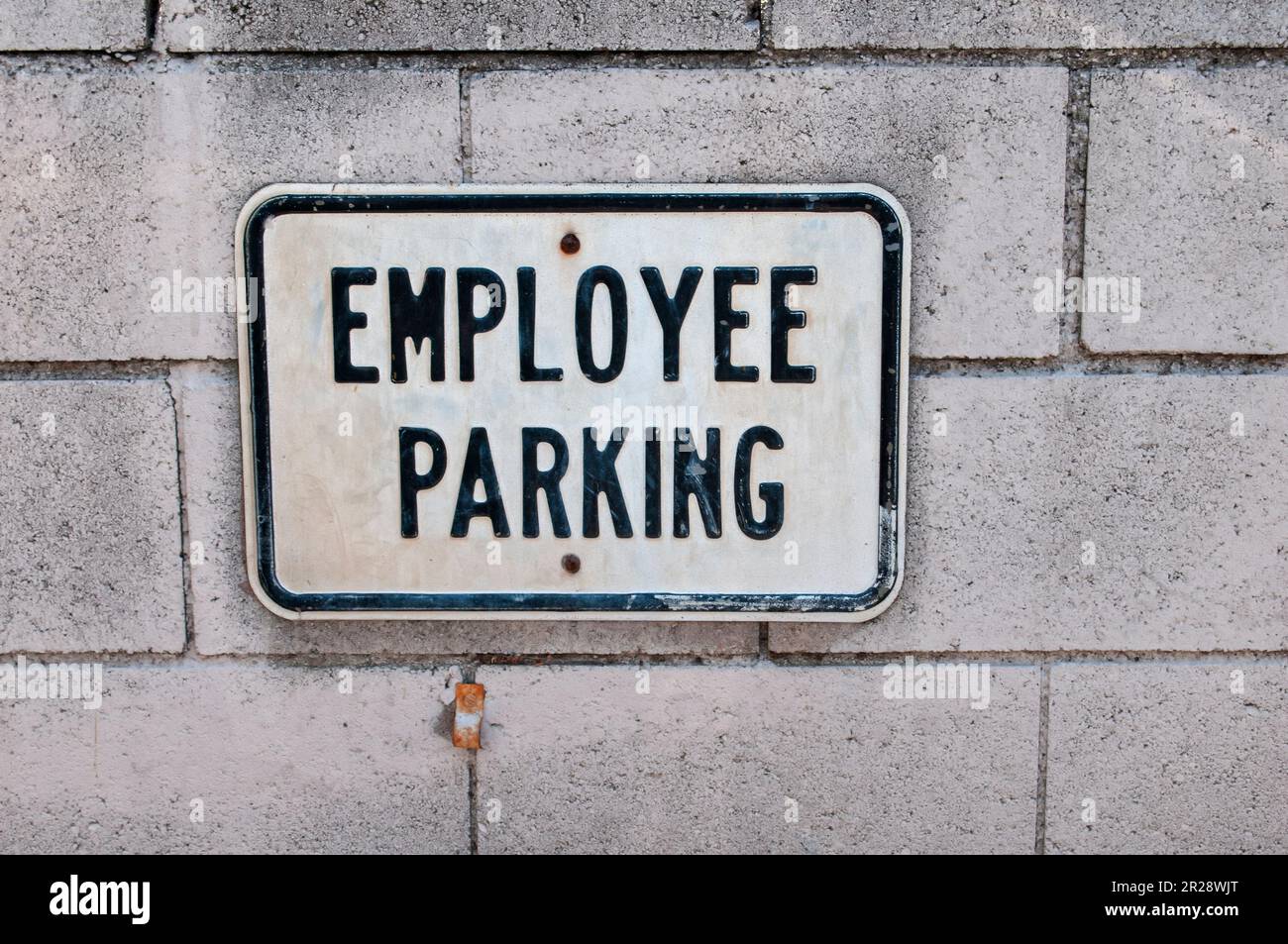 Employee parking sign on the white concrete brick wall Stock Photo