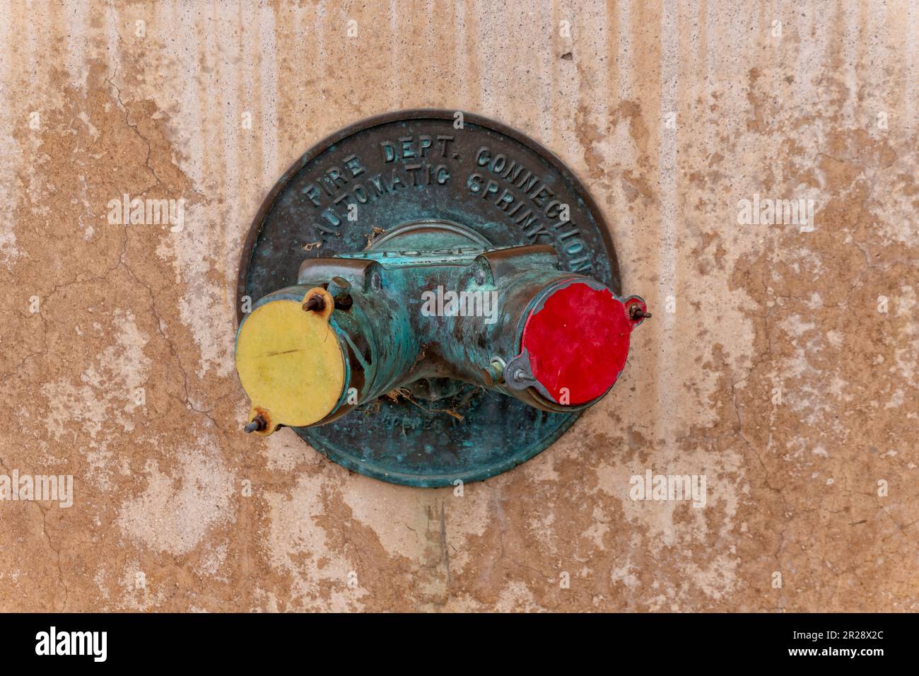 Old standpipe fire department connection on the weathered cracked wall ...