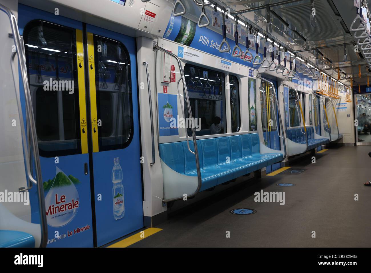 Young Indonesian woman wearing a mask in an empty Mass Rapid Transit carriage with Le Minerale advert displayed over her head in Jakarta, Indonesia Stock Photo