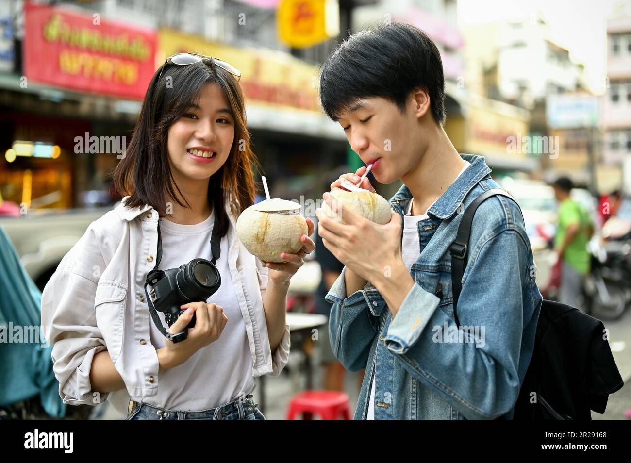 Chiang Mai, Thailand - May 17 2023: Happy young Asian tourist couple enjoying their fresh coconut drink at a Chinatown in Chiang Mai. Stock Photo