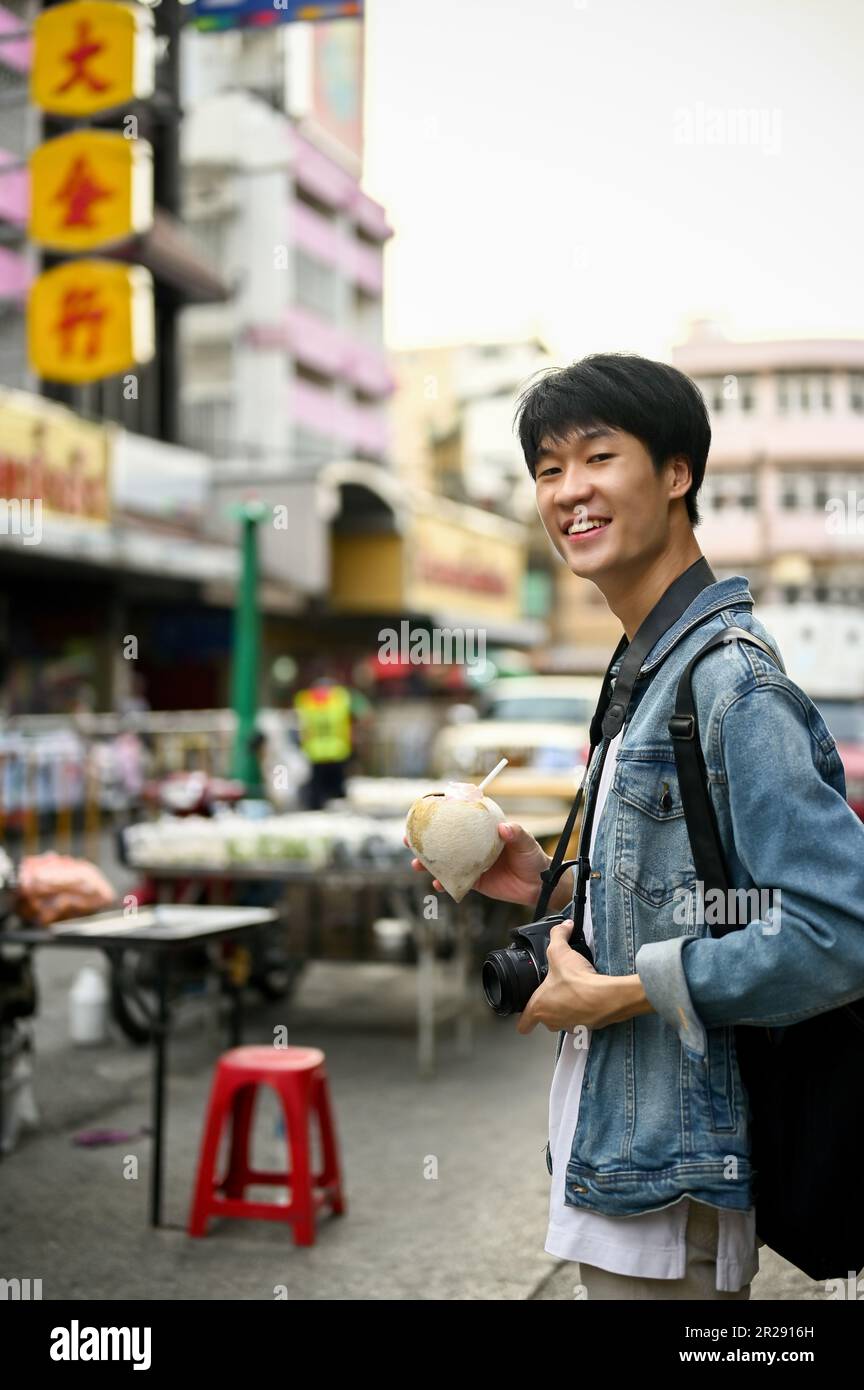 Chiang Mai, Thailand - May 17 2023: Portrait of a handsome and smiling young male tourist in a Chinatown street. Solo traveler concept Stock Photo