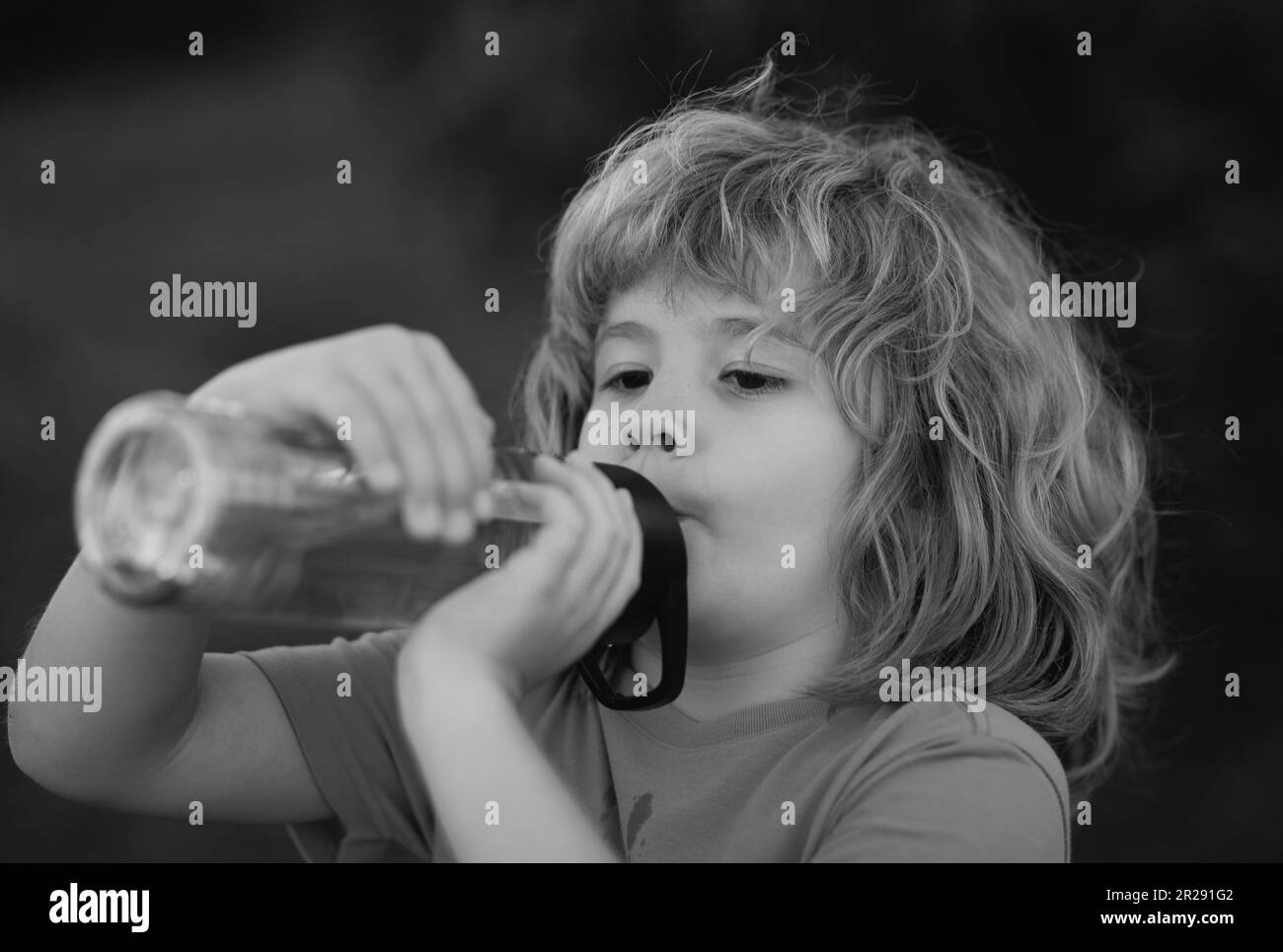 Child drinking water from bottle outdoor in park. Kid drinking. Stock Photo