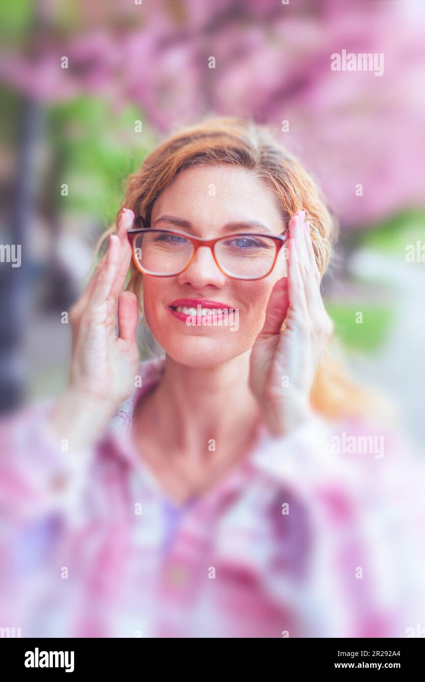 30s Caucasian woman put on eyeglasses to see clearly outdoors Stock Photo