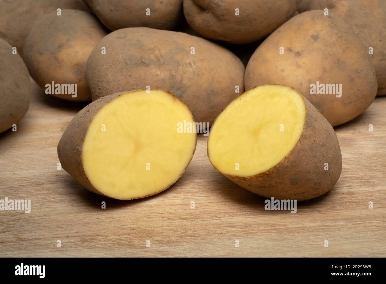 Dutch variety potato called Bintje whole and halved on wooden background close up Stock Photo