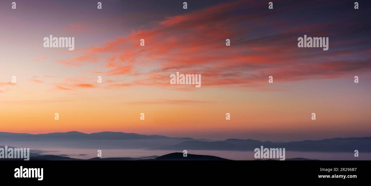 panorama of heavens at dawn. clouds in red and orange colors of a rising sun on a blue sky Stock Photo