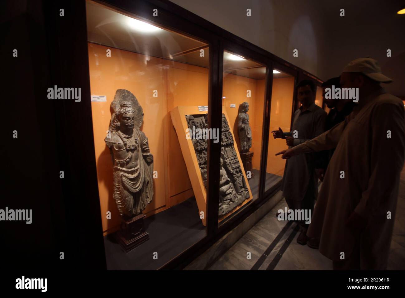 Visitors look at artifacts displayed in glass cases at the Peshawar
