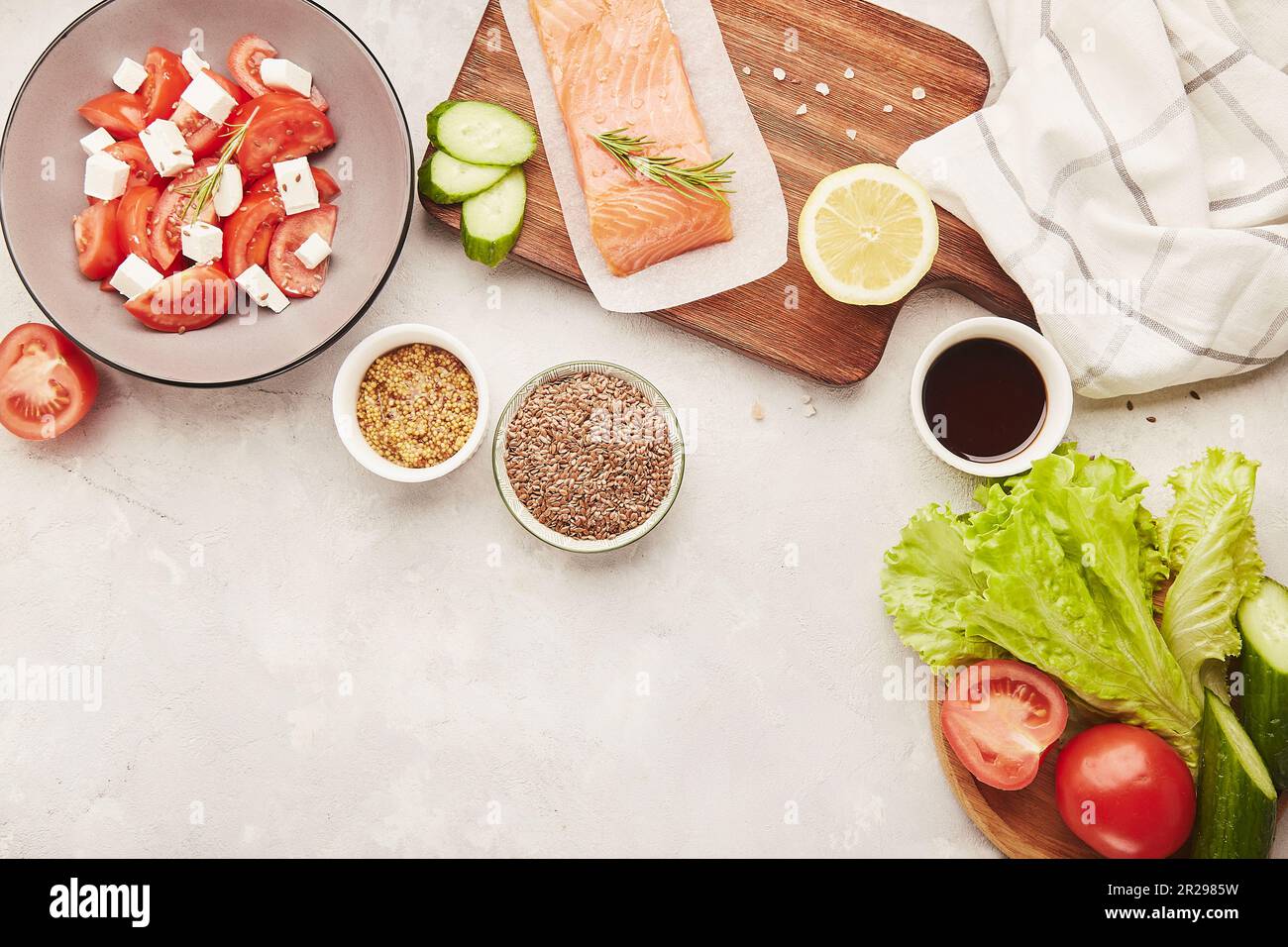 Ingredients for Ketogenic, Paleo, FODMAP diet menu concept. Fruits, vegetables, smoked salmon, salad with feta and greens on wooden cutting board Stock Photo