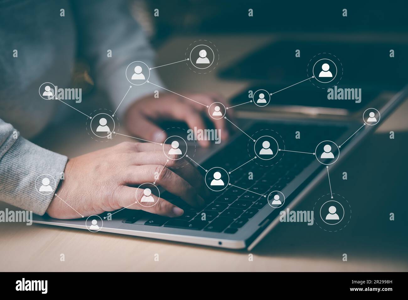 Hand using laptop to play social media, a mobile phone with a notification people icon,Social Distancing ,Working From Home concept,international cons Stock Photo