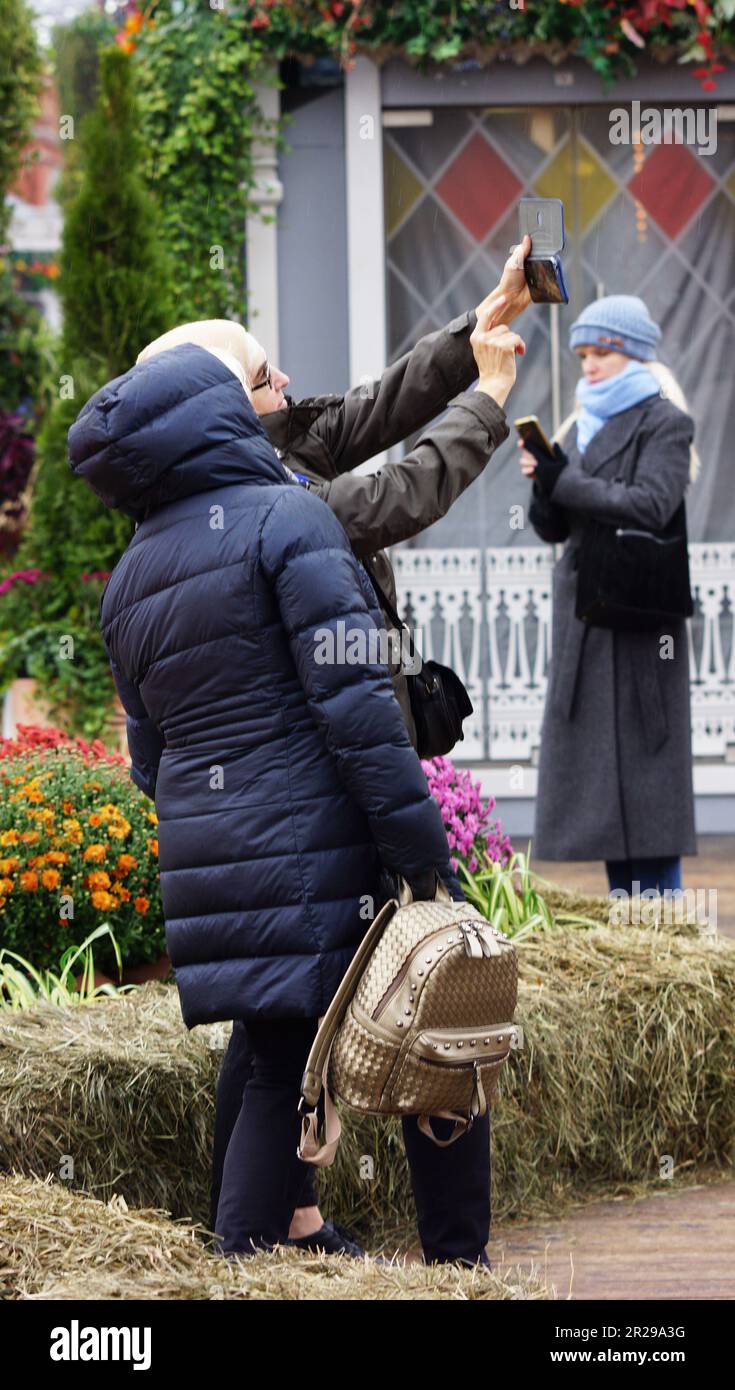 russian women taking selfies on a harvest market in Moscow, Russia. Frauen machen Selfies aur einem Herbstmarkt in Moskau, Russland Stock Photo