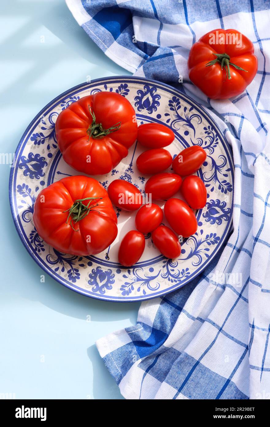 Different kinds of ripe big red tomatoes and cherry tomatoes on a plate ...