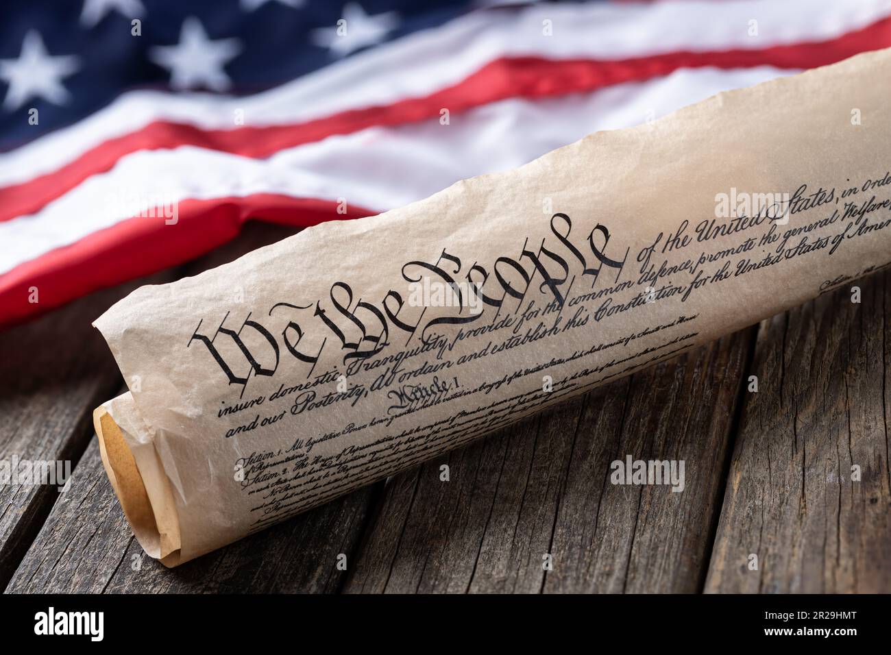 United States constitution with American flag in background on rustic wooden table Stock Photo